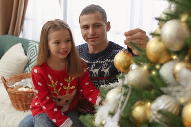 Father with daughter decorating Christmas tree at home