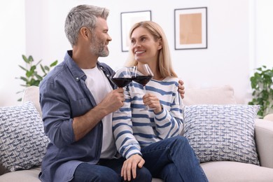 Happy affectionate couple with glasses of wine on sofa at home, space for text. Romantic date
