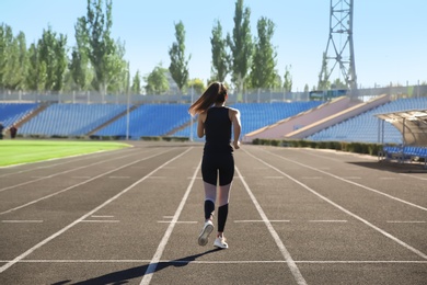 Photo of Sporty woman running at stadium on sunny morning