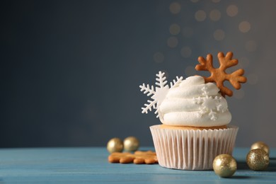 Tasty Christmas cupcake with snowflakes and festive decor on light blue wooden table. Space for text