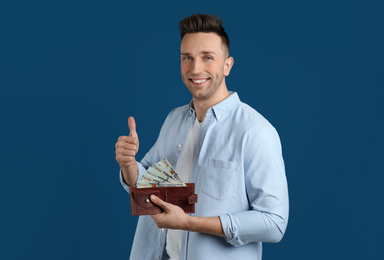 Happy man with cash money and wallet on blue background