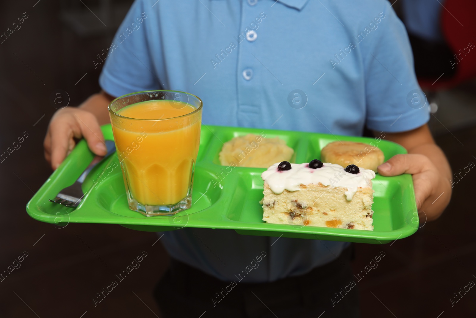 Photo of Boy holding tray with healthy food in school canteen, closeup