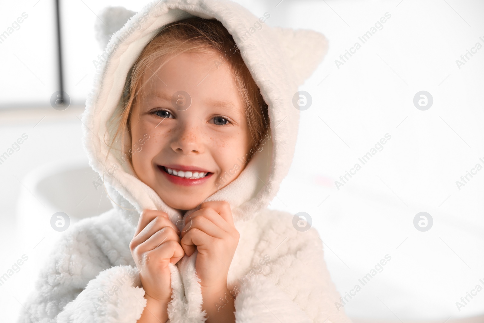 Photo of Cute little girl in bathroom. Space for text