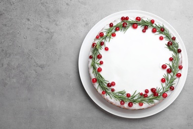 Traditional Christmas cake decorated with rosemary and cranberries on light grey table, top view. Space for text