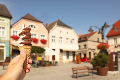 Woman holding delicious ice cream in wafer cone outdoors, closeup. Space for text