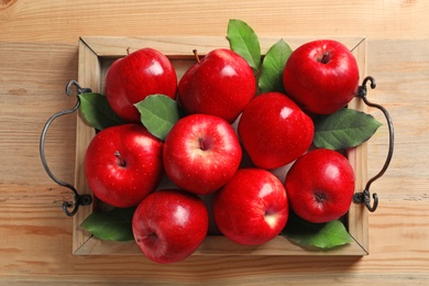 Tray with ripe red apples on wooden background