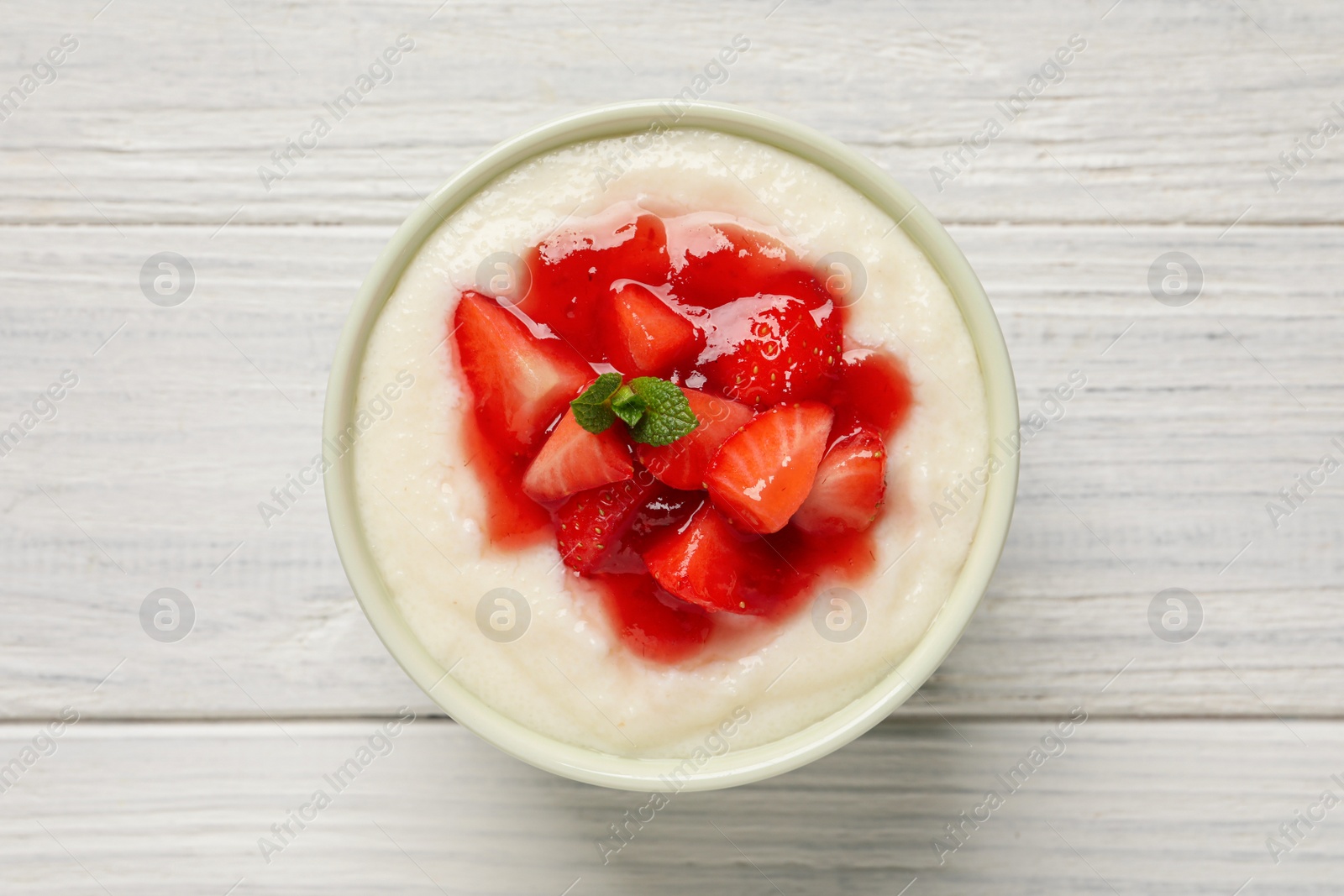 Photo of Delicious semolina pudding with strawberries and jam on white wooden table, top view