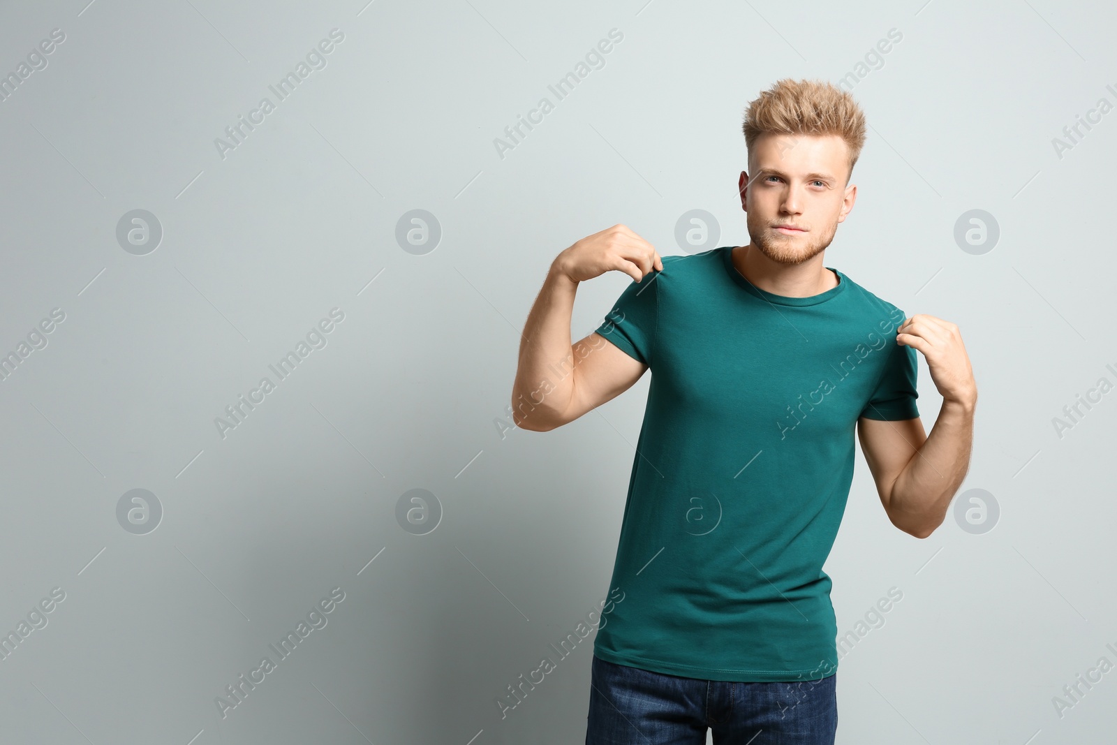 Photo of Young man wearing blank t-shirt on light background. Mockup for design