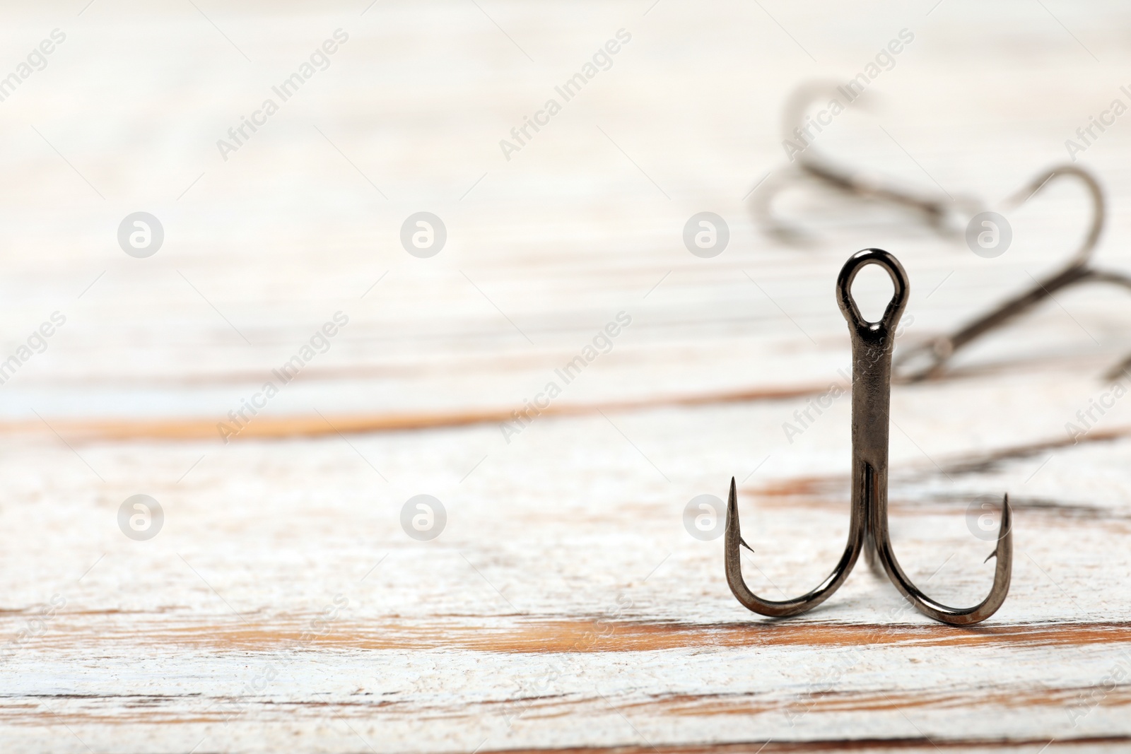 Photo of Fishing hook on wooden table. Space for text