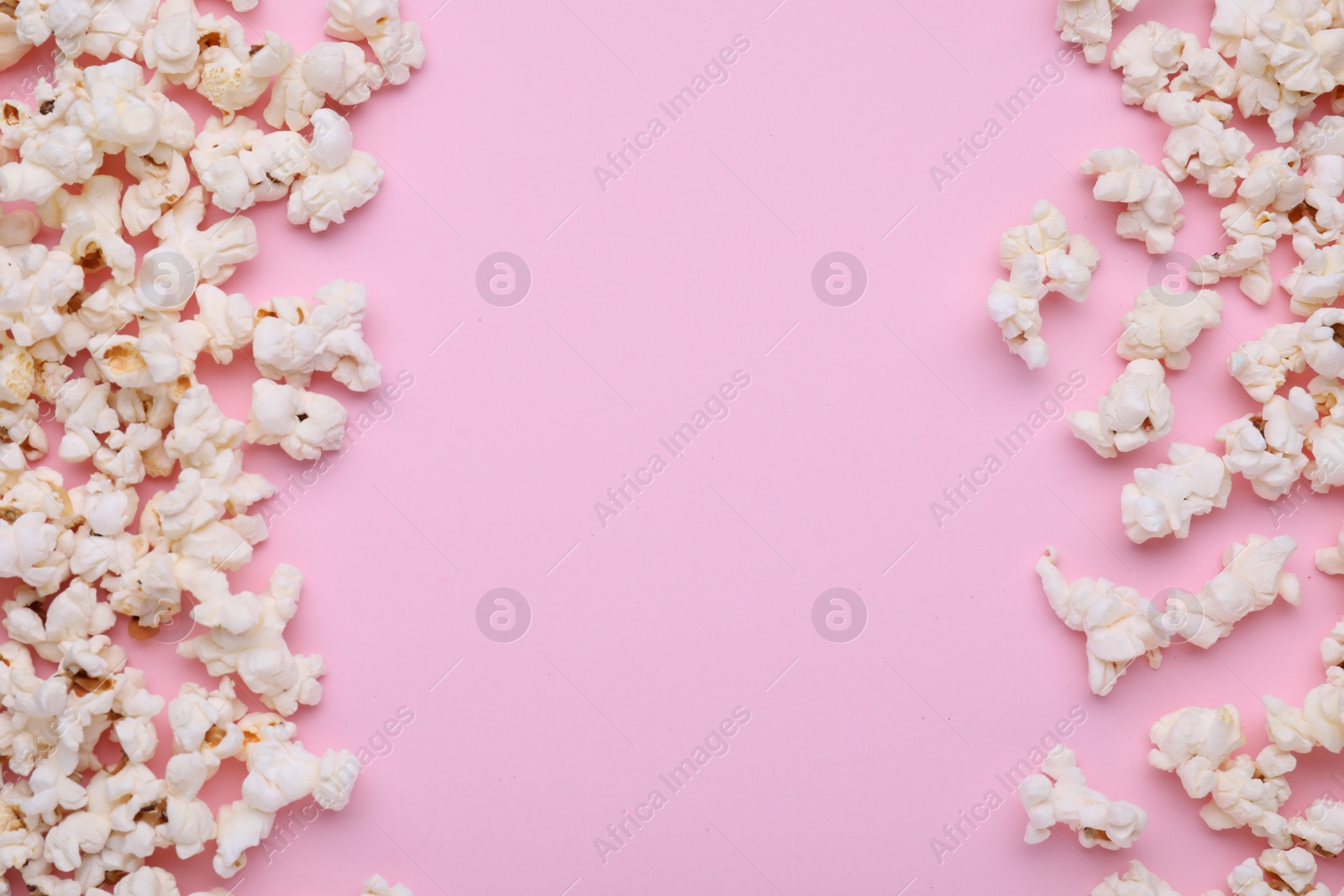 Photo of Tasty popcorn scattered on pink background, flat lay. Space for text