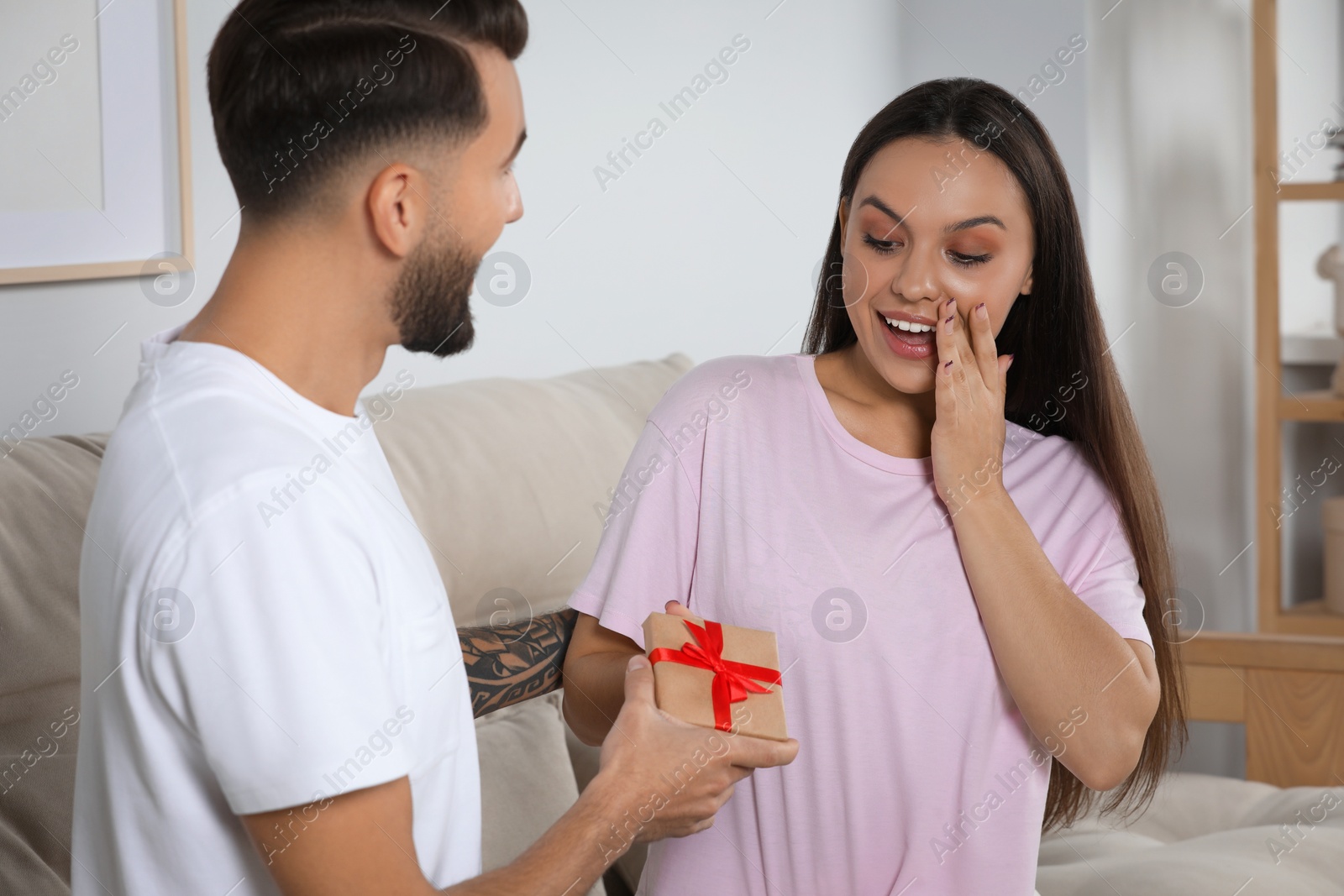 Photo of Man presenting gift to his girlfriend at home