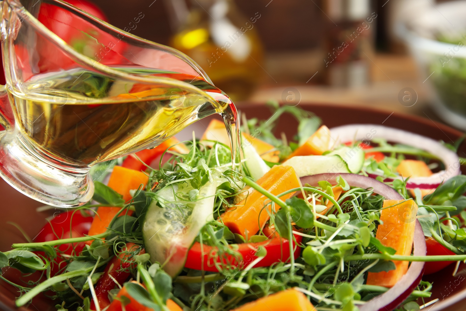 Photo of Adding dressing to delicious vegetable salad with microgreen, closeup