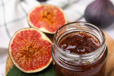 Photo of Tasty sweet fig jam in jar and fruits on table, closeup