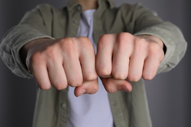 Man showing fists with space for tattoo on grey background, closeup