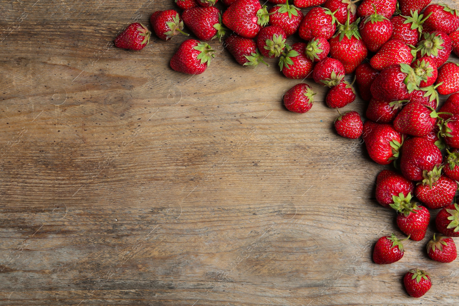 Photo of Delicious ripe strawberries on wooden table, flat lay. Space for text