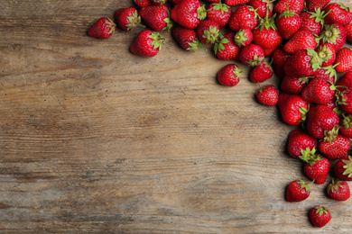 Delicious ripe strawberries on wooden table, flat lay. Space for text