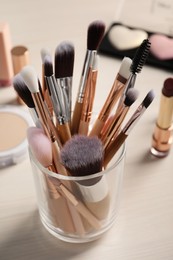 Photo of Set of professional brushes and makeup products on wooden table