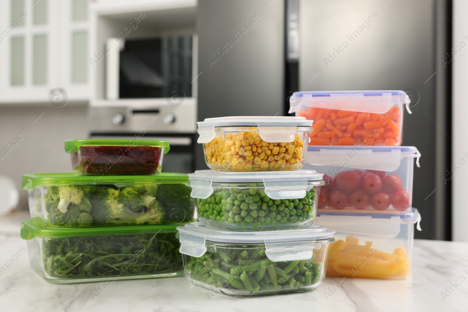 Photo of Glass and plastic containers with different fresh products on white marble table in kitchen. Food storage