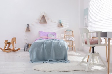 Comfortable bed with pink linens in children's room