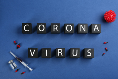 Photo of Wooden cubes with words CORONA VIRUS and medicine on blue background, flat lay