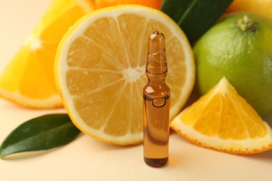 Skincare ampoule with vitamin C, different citrus fruits and leaves on beige background, closeup