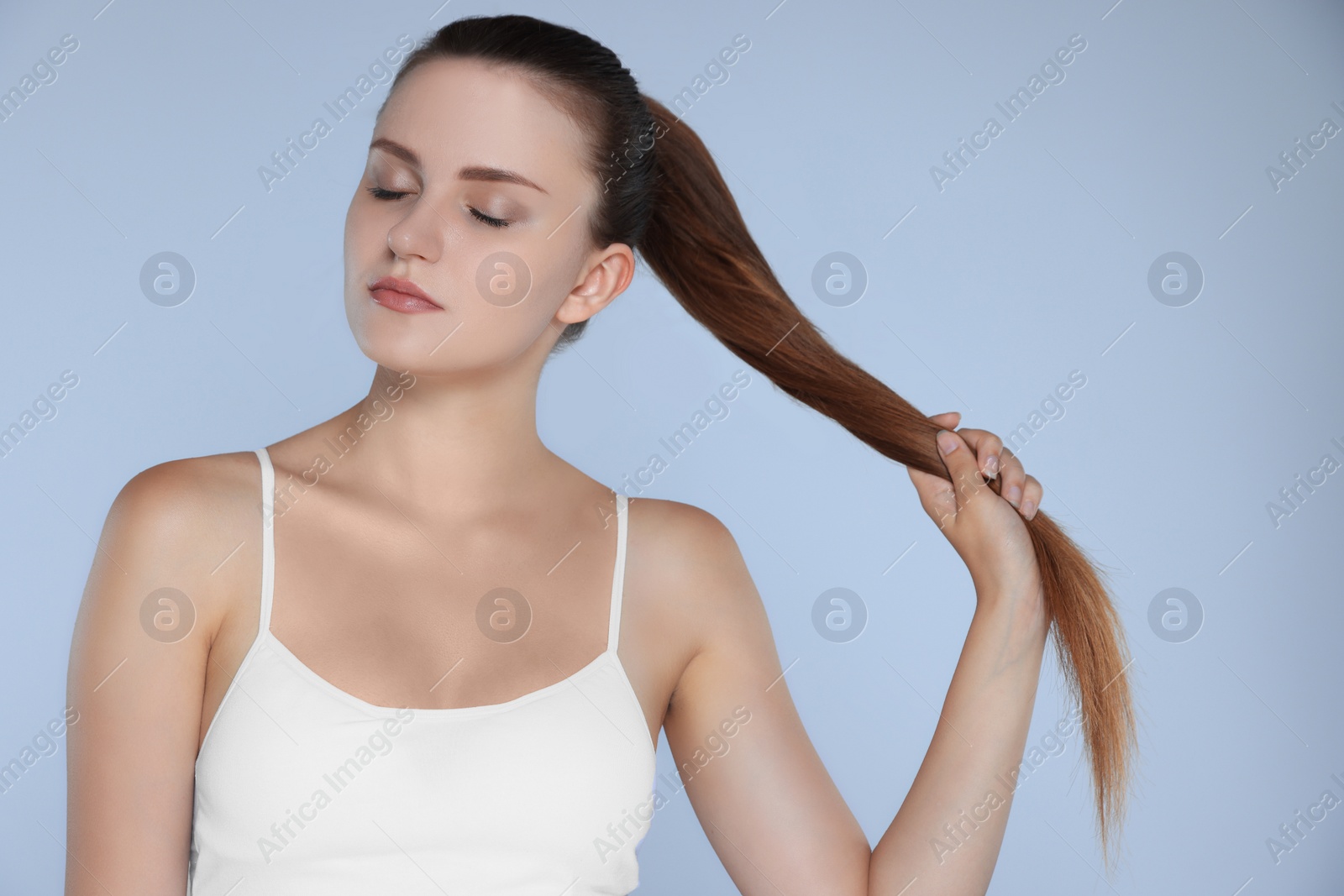 Photo of Young woman with strong healthy hair on light blue background