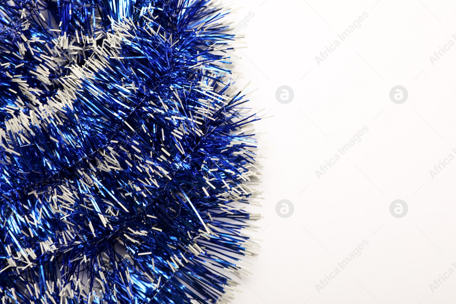 Photo of Bright blue tinsel on light background, top view.. Space for text