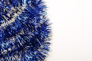 Bright blue tinsel on light background, top view.. Space for text