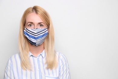 Woman wearing handmade cloth mask on white background, space for text. Personal protective equipment during COVID-19 pandemic