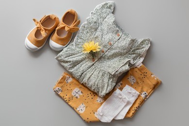 Photo of Stylish child clothes and shoes on grey background, flat lay