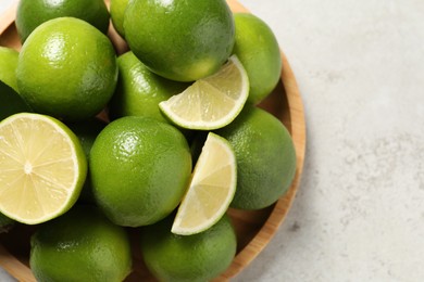 Photo of Whole and cut fresh limes on light table, top view. Space for text