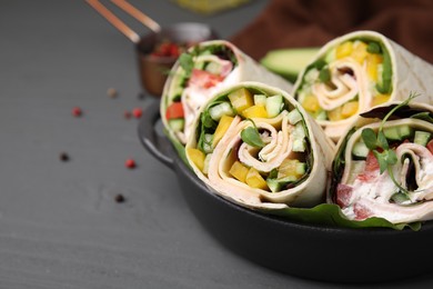 Delicious sandwich wraps with fresh vegetables on grey table, closeup. Space for text