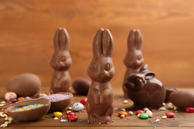 Photo of Chocolate Easter bunnies, candies and eggs on wooden table