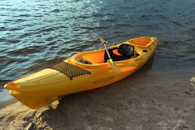 Photo of Beautiful modern yellow kayak with paddle on beach