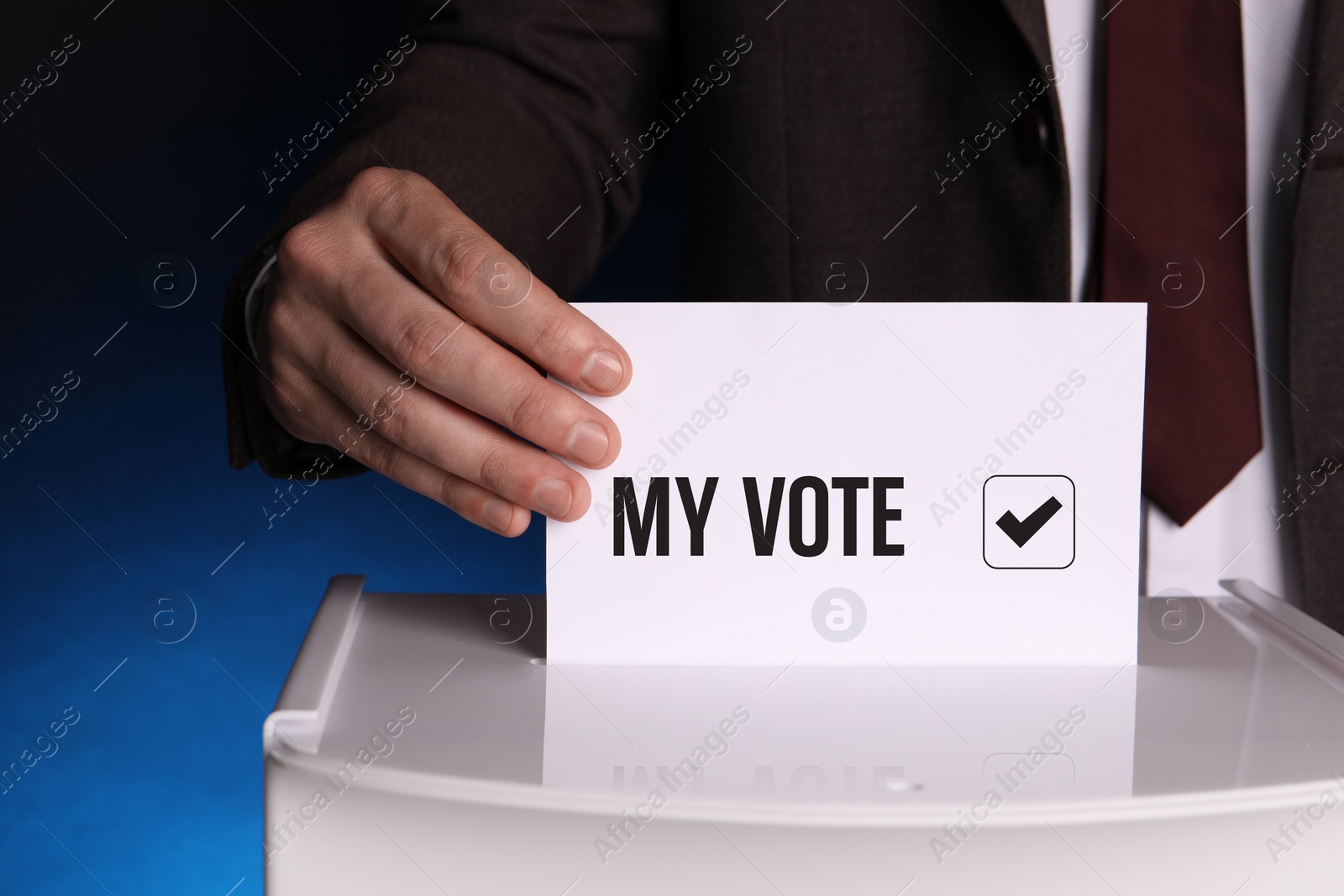 Image of Man putting paper with text My Vote and tick into ballot box on dark blue background