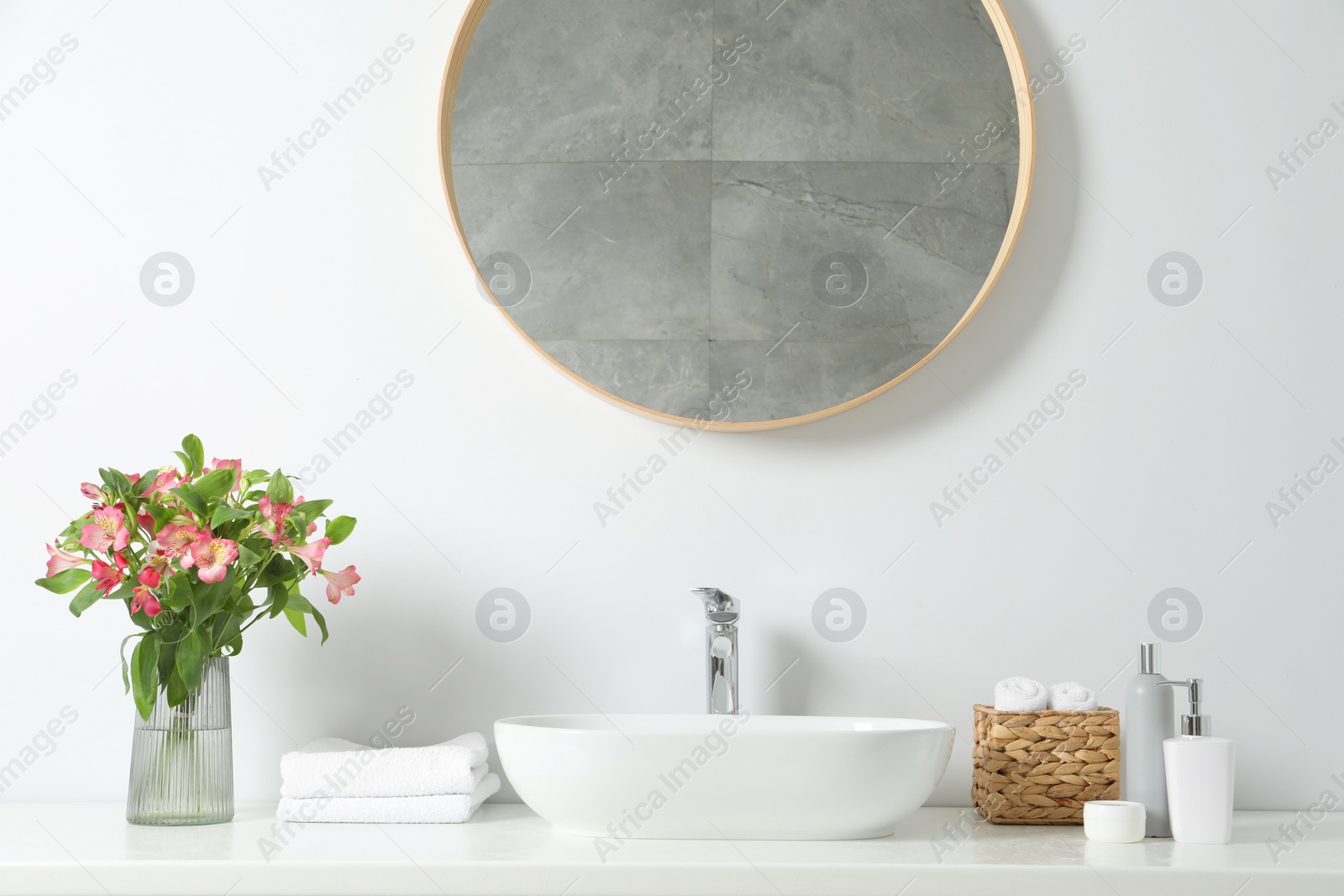 Photo of Vase with beautiful Alstroemeria flowers and toiletries near sink in bathroom