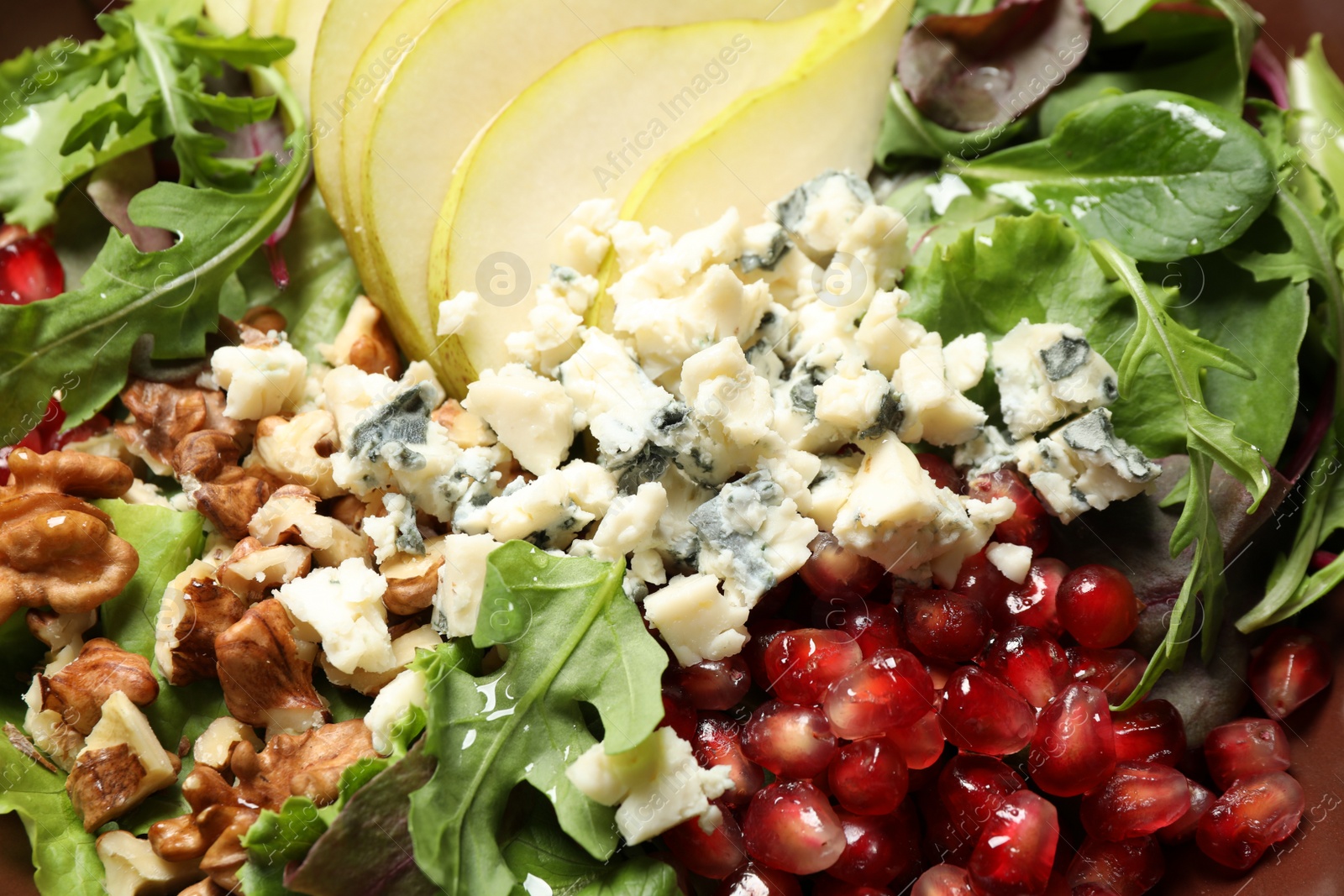 Photo of Tasty salad with pear slices, blue cheese, walnuts and pomegranate seeds as background, closeup