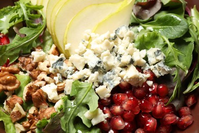 Photo of Tasty salad with pear slices, blue cheese, walnuts and pomegranate seeds as background, closeup