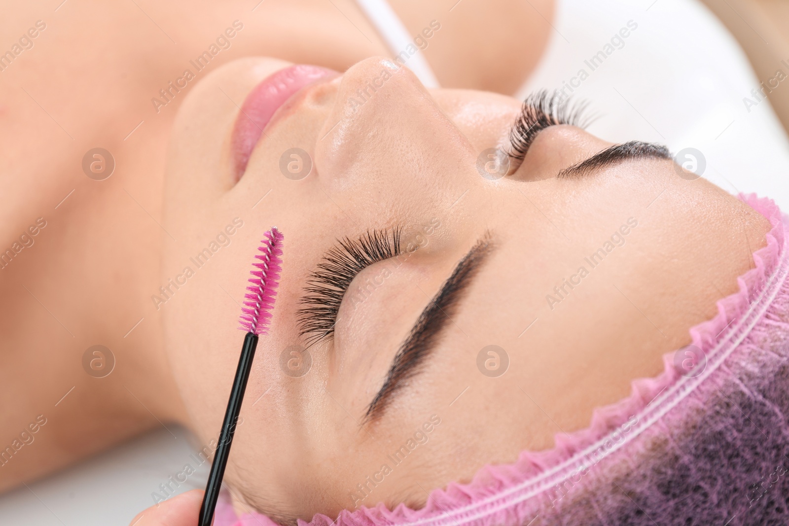 Photo of Young woman undergoing eyelash extensions procedure, closeup