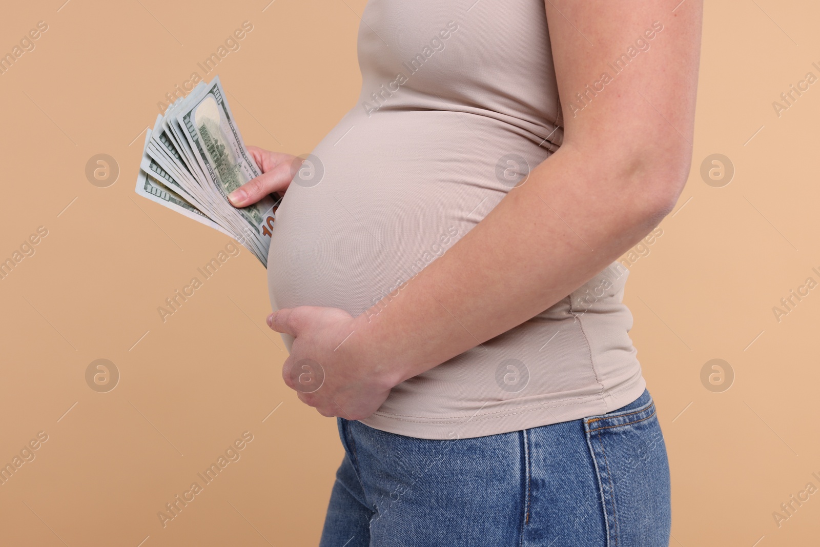 Photo of Surrogate mother. Pregnant woman with dollar banknotes on beige background, closeup