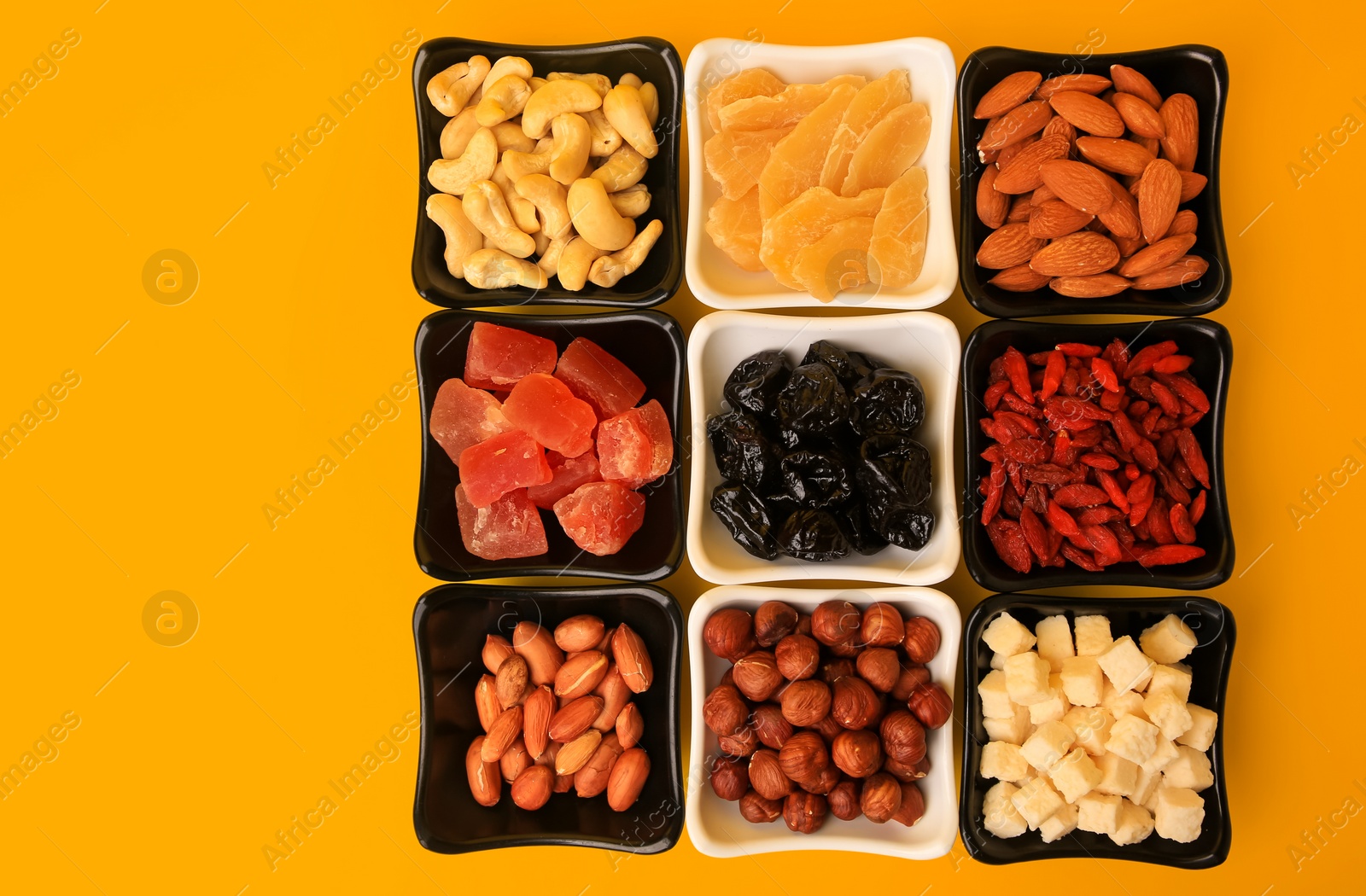 Photo of Bowls with dried fruits and nuts on yellow background, flat lay. Space for text