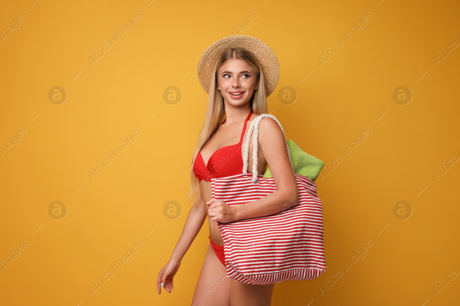 Photo of Pretty young woman wearing stylish bikini with bag on orange background