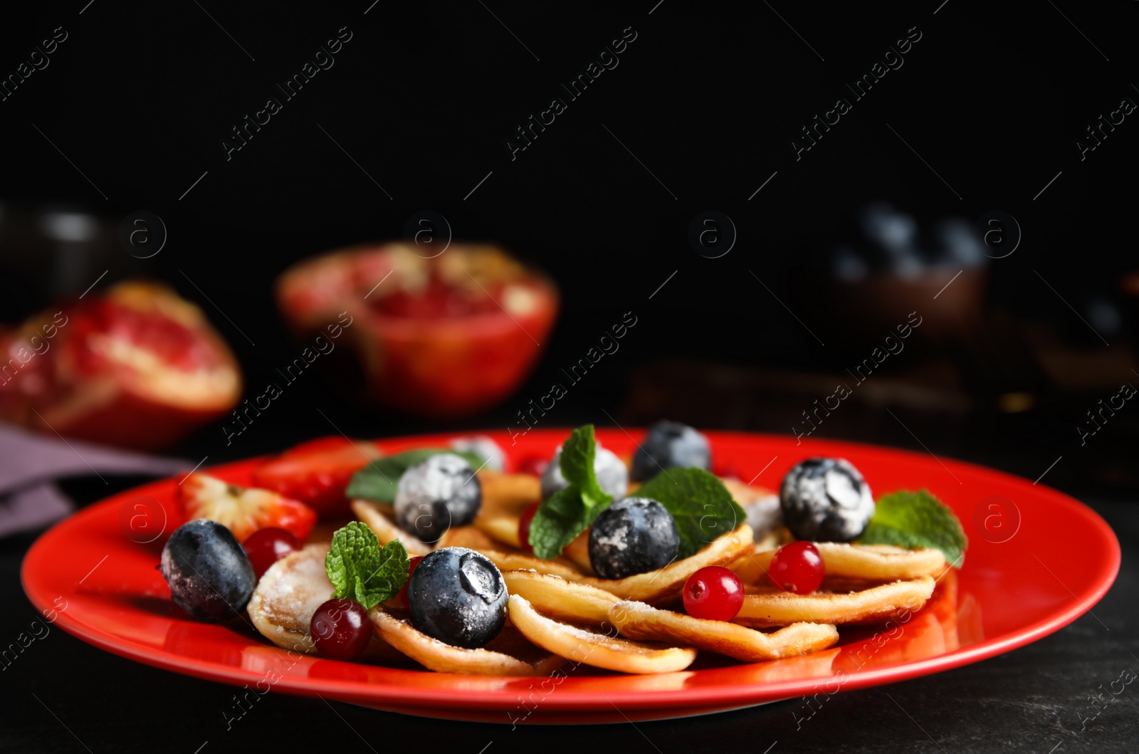 Photo of Cereal pancakes with berries and mint on black table, closeup