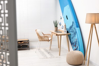Photo of SUP board and workplace in room. Interior design