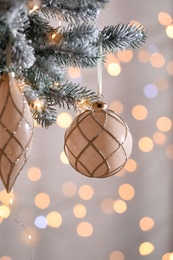 Photo of Christmas tree decorated with holiday baubles against blurred lights, closeup