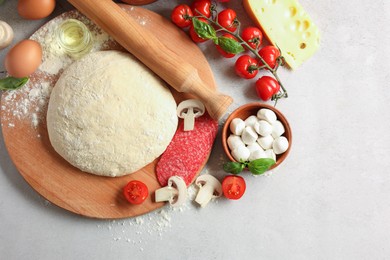 Photo of Pizza dough, products and rolling pin on gray textured table, flat lay