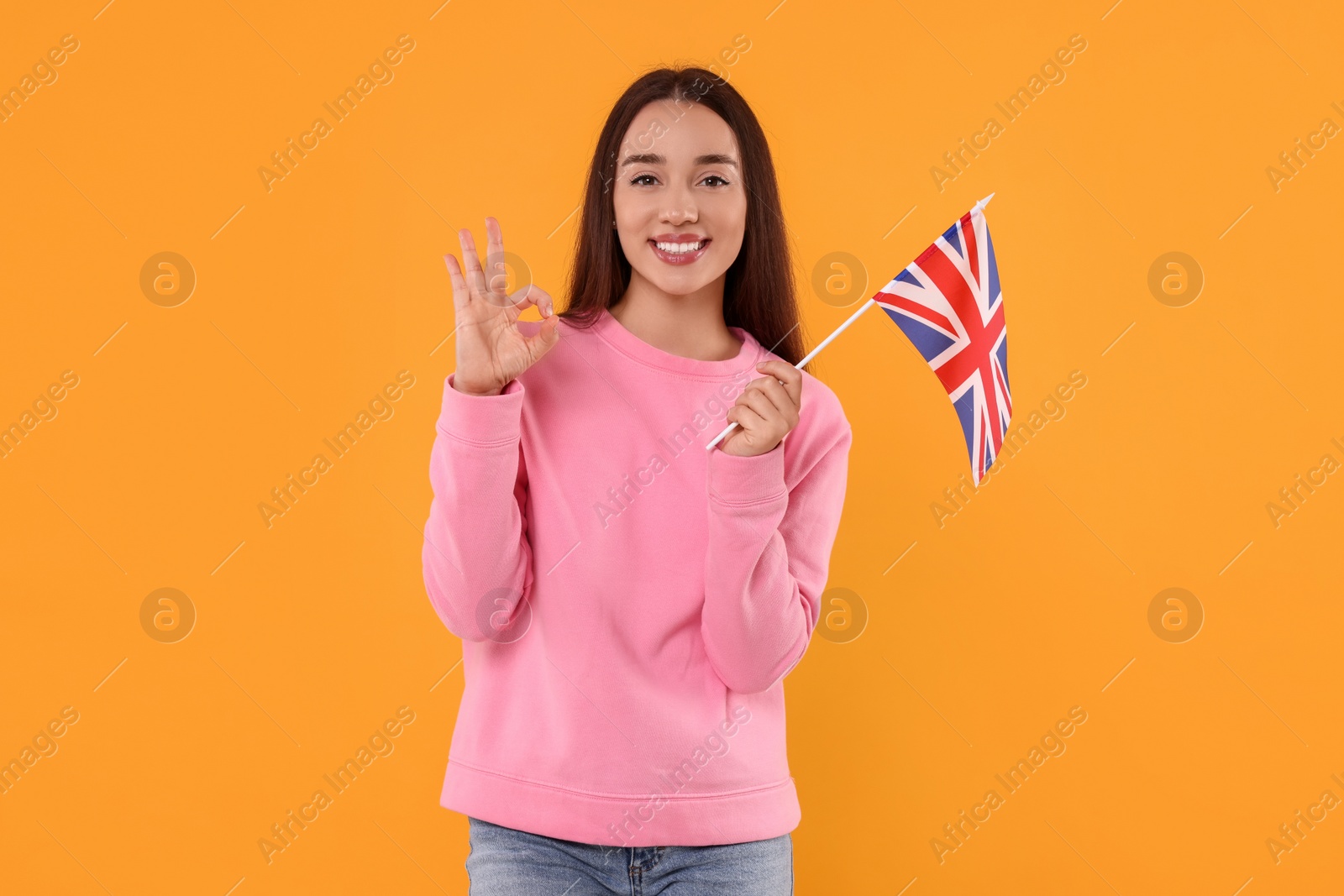 Photo of Young with flag of United Kingdom showing ok gesture on orange background