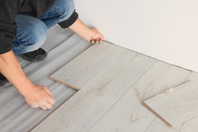 Photo of Professional worker installing new laminate flooring, closeup