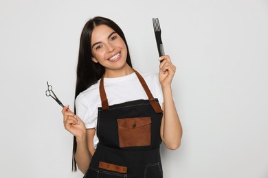 Photo of Portrait of happy hairdresser with professional scissors and comb on light background