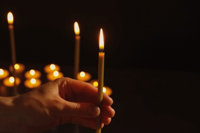 Photo of Young person holding burning candle in darkness, closeup